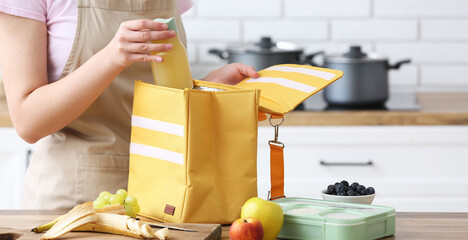 Wall Mural - Woman packing school lunch for her child in kitchen