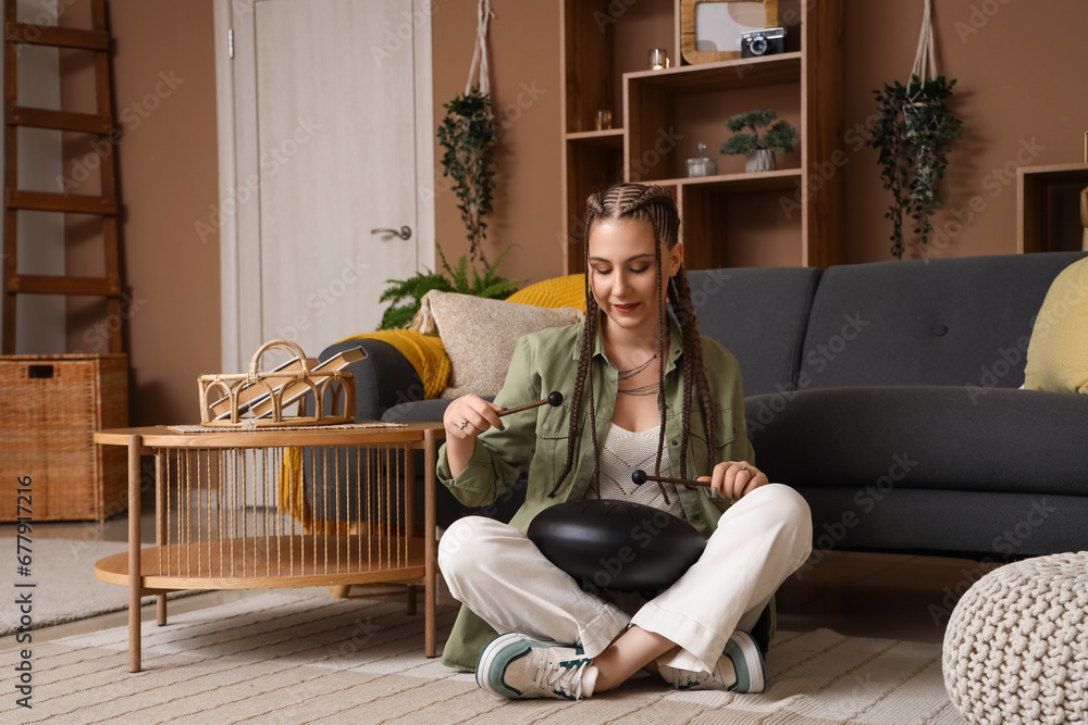 Young woman with sticks playing glucophone at home