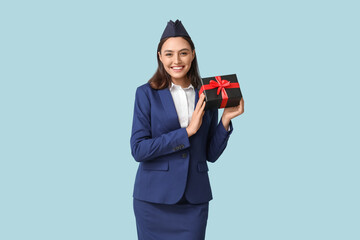 Canvas Print - Beautiful stewardess with gift box on blue background