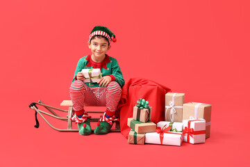 Sticker - Cute little elf with sled and Christmas gifts on red background