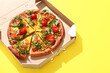 © Pixel-Shot - Cardboard box of delicious pizza with tomatoes and arugula on yellow background