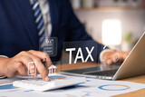 Fototapeta  - Tax and Vat concept. Government, state taxes concept. Businesman using calculator and laptop to complete Individual income tax return form online for tax payment. Data analysis, financial research.