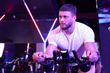 Canvas Print - Young man training on exercise bike in fitness club