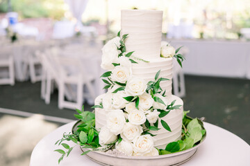 Wall Mural - A beautiful three-tiered wedding cake decorated with white roses and greenery. 