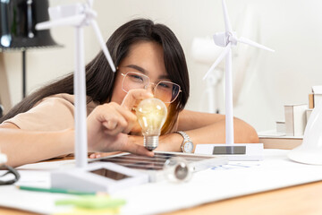 Wall Mural - Woman holds a light bulb and looks at the light while thinking about natural energy engineering in inspirational design.