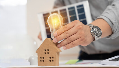 Wall Mural - Concept working for clean energy and saving power in nature. hand holding light bulb on the house model and solar panel.