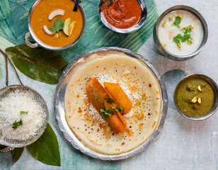 Wall Mural - A top-down shot of Indian dosa captures the thin and crispy rice crepe filled with spiced potatoes, served with coconut chutney and sambar, showcasing the diversity of flavors in South Indian cuisine.