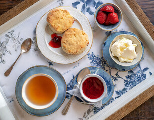 Wall Mural - A top-down shot of a British afternoon tea features a classic cup of Earl Grey tea served with scones, clotted cream, and strawberry jam, embodying the timeless elegance of British teatime.