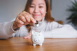 © Farknot Architect - Portrait image of a young woman putting coins into piggy bank for saving money concept
