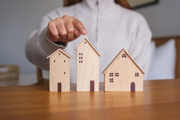 Wall Mural - Closeup image of a woman pointing finger at wooden house models