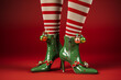 Leinwandbild Motiv Close up of festive christmas elf legs with striped tights on a bright coloured background