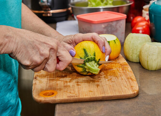 Sticker - Chef cuts round zucchini on wooden board in the home kitchen