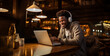 © Gonzalo - Happy ethnic guy in headphones smiling and writing in notebook while sitting at table