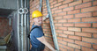 Portrait of man using special construction equipment to remove any concrete masses to make wall made of red brick smooth and easy to plaster surface. Male posing in unfinished room. Building concept