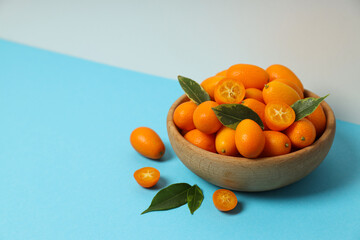 Sticker - Kumquat in wooden bowl on blue table on white background, space for text