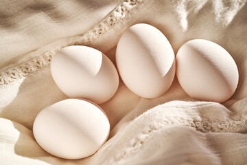 Wall Mural - White chicken eggs on a white linen towel close-up.