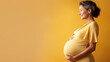 Pregnant mature woman on pastel yellow background with copy space. Late pregnancy, gynecological services for management of pregnancy, In Vitro Fertilization.