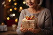 © mitarart - Senior woman holds a beautifully wrapped Christmas present in her hands.