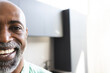 © Wavebreak Media - Half portrait of happy bald african american mature man with beard smiling in sunny room, copy space