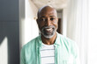 © Wavebreak Media - Portrait of happy bald african american mature man with beard smiling in sunny room at home
