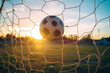scoring chance - the ball flies into the goal net on an amateur football field at sunset