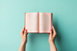 female hands holding an open book on a colored background.top view, copy space. library, bookstore and learning concept