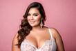 Happy sexy plus size fashion model in a white lace bra, beautiful fat woman with makeup and hairstyle in lingerie on pink background, body positive concept