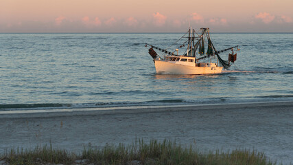 Shrimp boat along the North Carolina shoreline in the light of the setting sun.