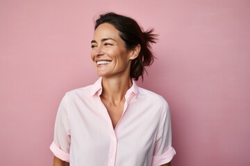 Wall Mural - Portrait of a joyful woman in her 40s wearing a simple cotton shirt against a pastel pink background. AI Generation