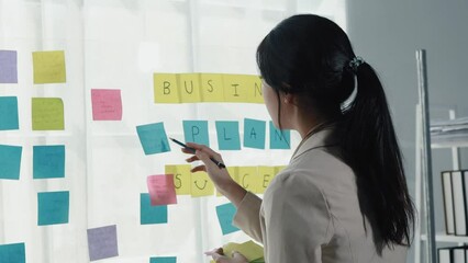 Wall Mural - Asian woman sitting in the office, businesswoman managing a startup company, planning marketing and finding ways to increase profits, managing sales growth, strategizing the company.