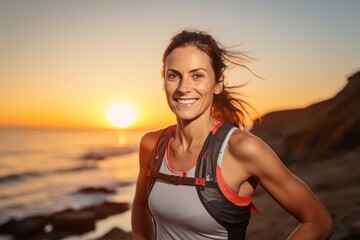 Wall Mural - Portrait of a content woman in her 30s wearing a lightweight running vest against a stunning sunset beach background. AI Generation