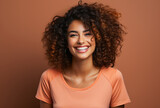 Fototapeta  - young pretty woman with curly hair laughs heartily into the camera in front of an orange background