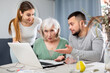 © JackF - Young adult son and his wife giving help with laptop to stressed elderly mother at home
