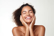 © Jasmina - Portrait of a young smiling black woman touching her flawless glowy skin on soft white background, skincare concept
