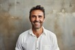 © CogniLens - Portrait of a smiling man in his 40s wearing a simple cotton shirt against a bare concrete or plaster wall. AI Generation