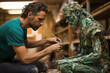 Artist sculpting striking piece from repurposed trash highlighting environmental consciousness 