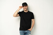 © opolja - Portrait of happy casual man smiling, guy wearing black t-shirt an d cap at white wall, Isolated on white background