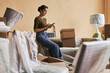 © Seventyfour - Young woman texting in smartphone or scrolling through list of contacts in spacious living room of new apartment while sitting on couch