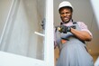 © Serhii - Young African Repairman In Overalls Installing Window