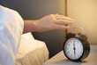© wor_woot - Woman hand pressing off alarm clock; Snooze clock at early morning, Lazy woman sleep on the bed