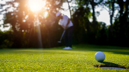 Wall Mural - Blurred golfer playing golf in the evening golf course, on sun set evening time.