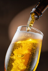 Canvas Print - Jet of beer out of the bottle is poured into a beer glass, causing a lot of bubbles and foam.