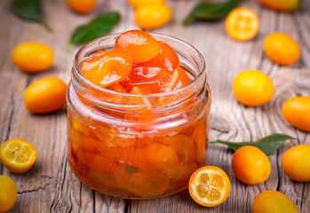 Wall Mural - Homemade kumquat jam in jar and fresh kumquats, top view