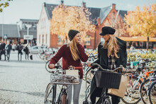 Two Young Caucasian Women Friends Shopping In Town With Bicycles