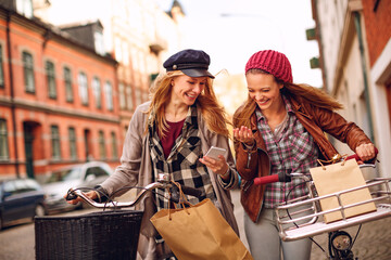 Wall Mural - Two young Caucasian women friends shopping in town with bicycles