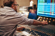 © Flamingo Images - Music producer working with audio equipment in a recording studio