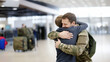 a military father embraces his teenage son as they reunite at the airport upon their arrival home from an armed conflict. the sacrifice of military life-risking your life to defend your country.