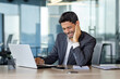 © Liubomir - Hindu businessman suffering from ear pain, sitting in the office at the desk in front of the laptop, holding his ear, wincing in pain, health concept.