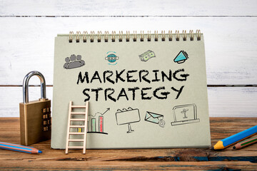 Wall Mural - Marketing Strategy. Green notepad on wooden texture table and white background