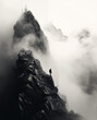 Man climbing a mountain in the mist. Conquering the summit even though the route is not always easy. Artistic monotone black and white photography.